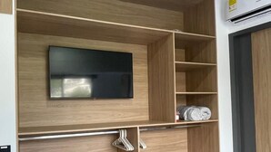 Un salon moderne doté d’un téléviseur encastré, d’étagères en bois et d’un sol carrelé de couleur grise.