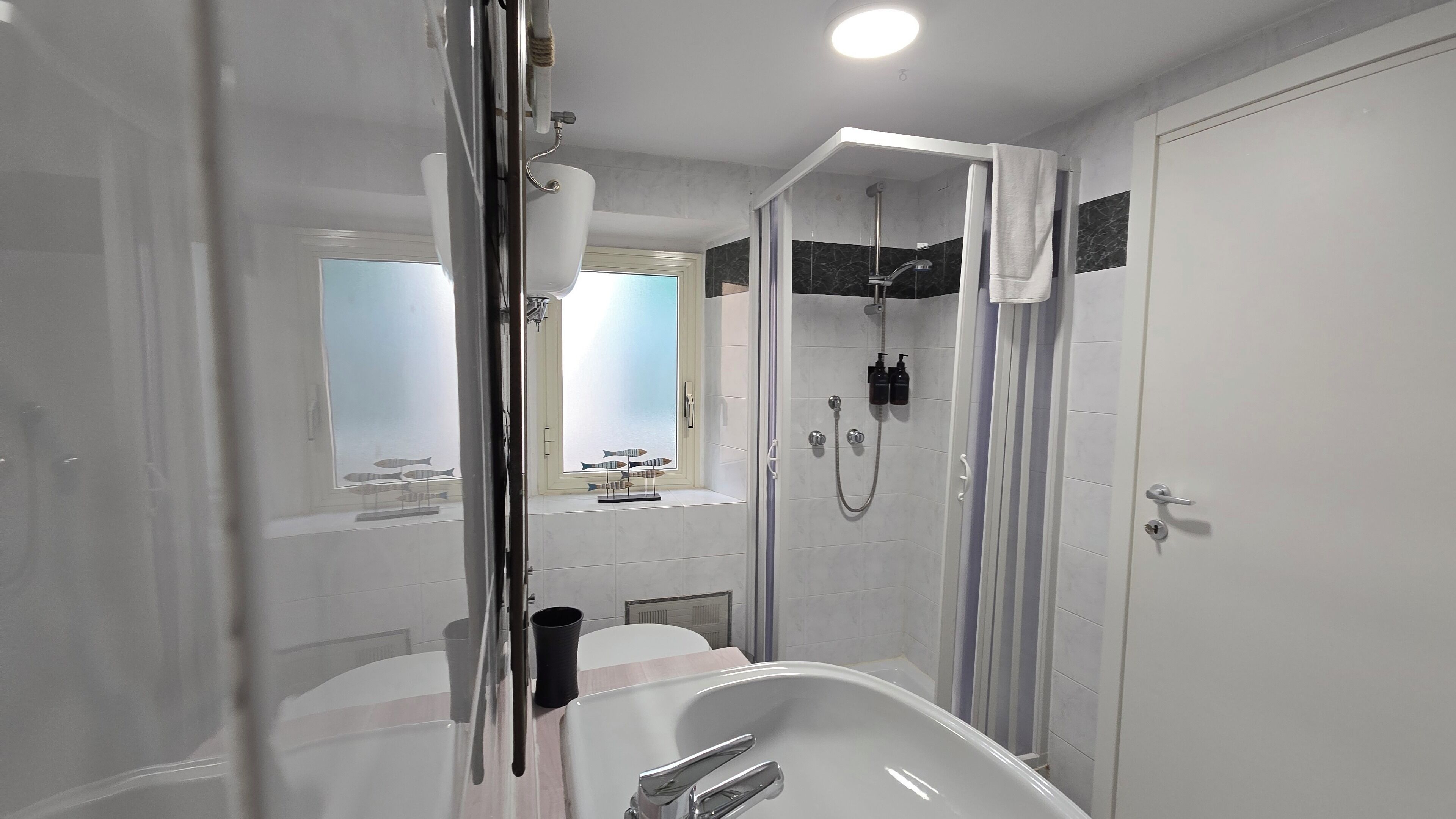 Une salle de bain moderne équipée d’une baignoire, d’une douche et d’une fenêtre donnant sur un aquarium.