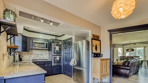 A modern kitchen with dark cabinetry, stainless steel appliances, and a wooden bar area. - Charming Oasis Apartment (El Paso)