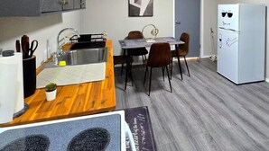 A compact kitchen with grey cabinets, a wooden countertop, a sink, and a dining area with chairs and a table. - Sunrise Sanctuary – El Paso (El Paso)