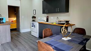 A compact kitchen with a stove, sink, and dark cabinets. There is a dining area with a table and chairs. - Sunrise Sanctuary – El Paso (El Paso)