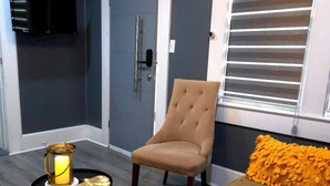 A living room with a beige armchair, a sofa, a small round table with a candle, and a decorative cushion. - Sunrise Sanctuary – El Paso (El Paso)