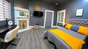 A bedroom with a bed, a desk, a chair, a television, and a fireplace. - Sunrise Sanctuary – El Paso (El Paso)