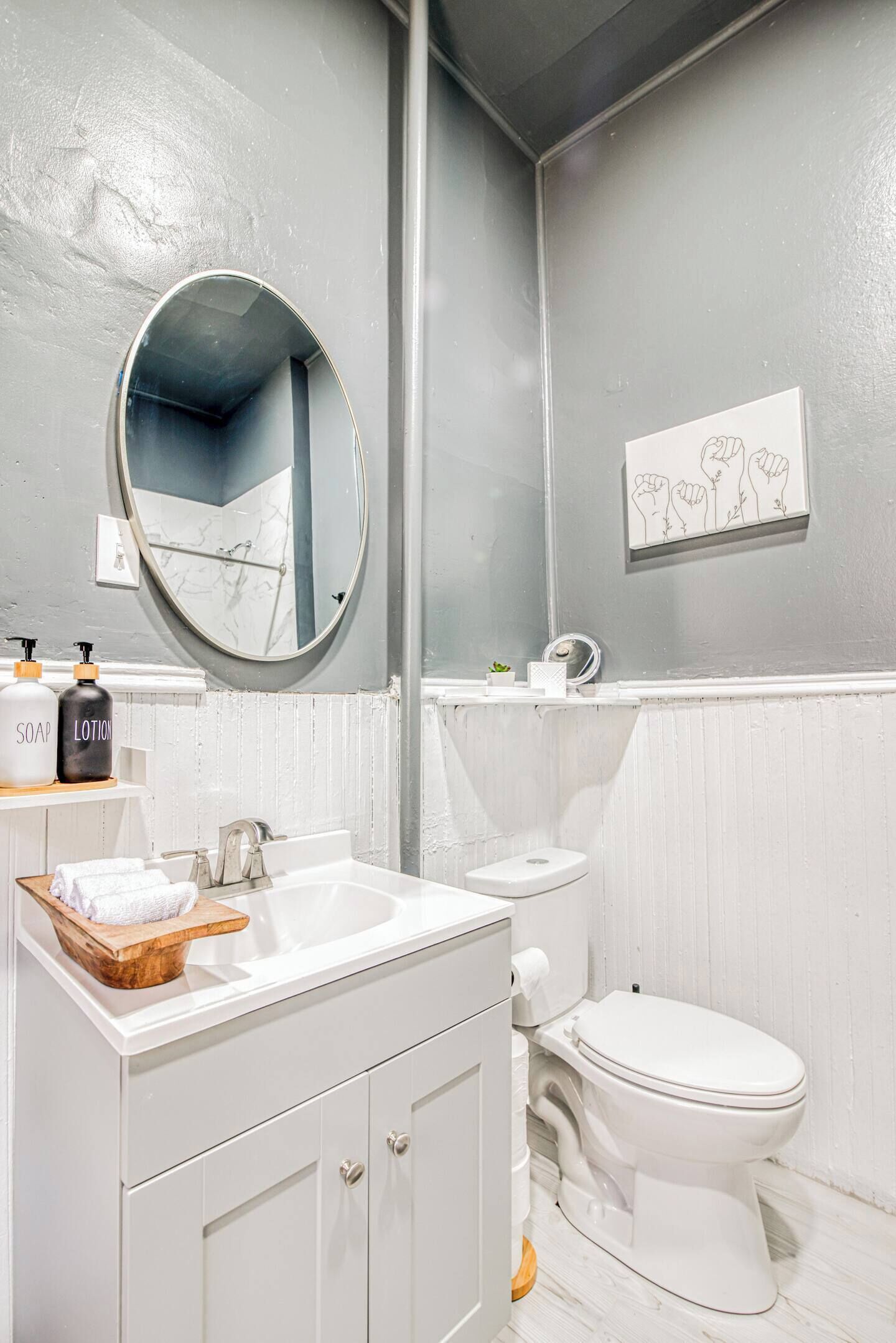 A bathroom with a white sink, a mirror, a toilet, and a shelf with toiletries.