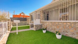 A house with a stone exterior, a white mailbox, and a well-maintained lawn with two potted plants. - Sunset Sanctuary - El Paso (El Paso)