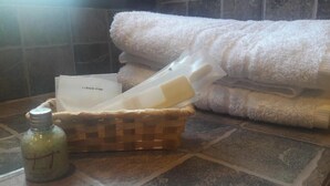 A bathroom with a tiled floor, a white towel, a basket with toiletries, and a bottle of lotion. - Vientonorte (Tilcara)