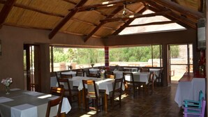 A dining area with tables and chairs, large windows, and a high ceiling. - Vientonorte (Tilcara)