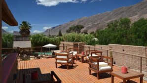 A wooden deck with outdoor seating, a pool, and a view of mountains. - Vientonorte (Tilcara)