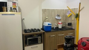 Una cocina compacta con estufa a gas, microondas, cafetera y licuadora sobre la encimera.