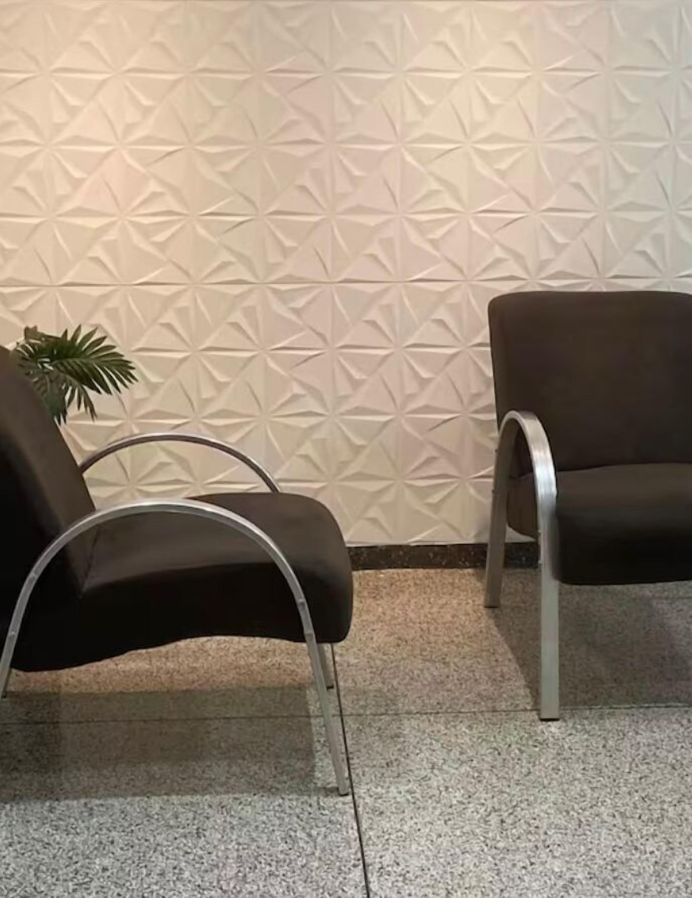 Dos sillas negras con estructura metálica, una pared con textura y una planta.