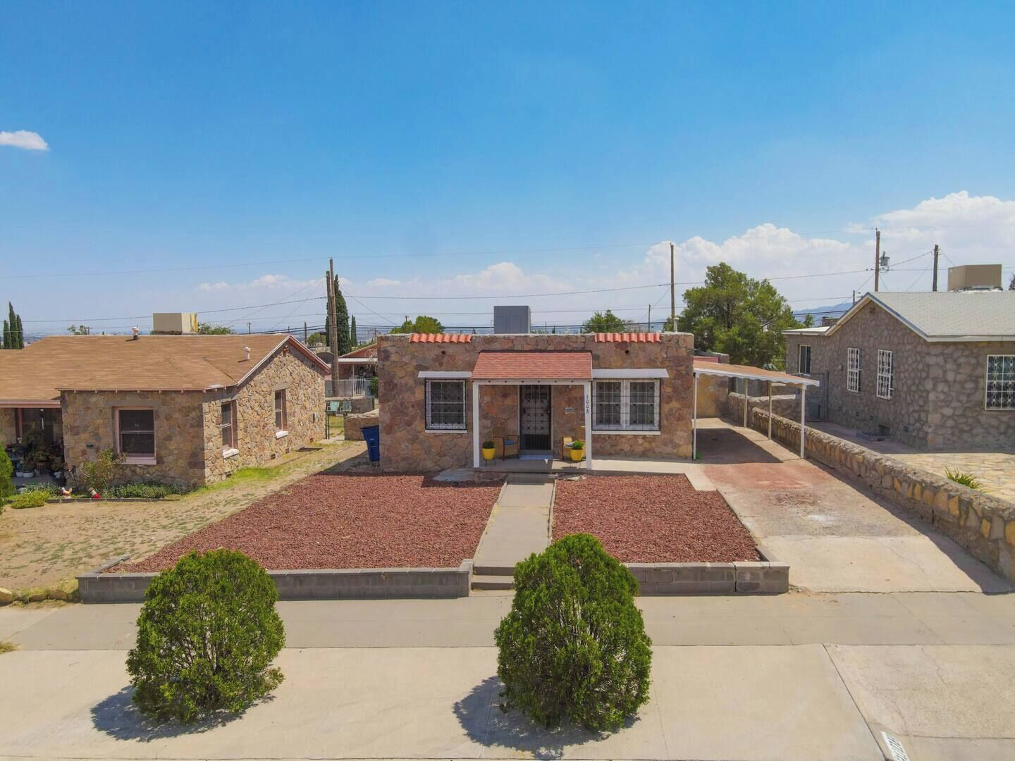 A stone building with a red-tiled roof, a small porch, and a paved driveway.