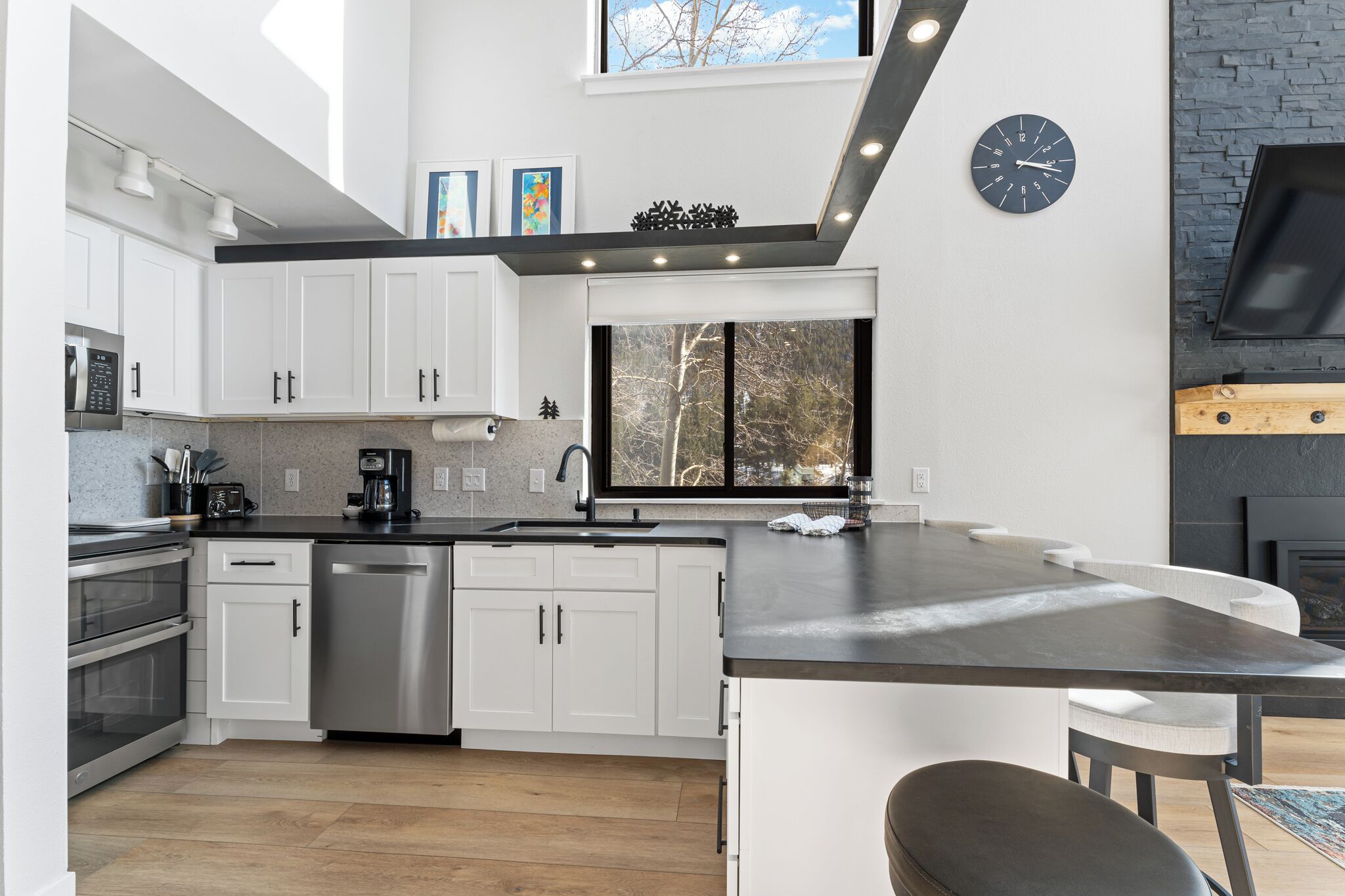 Una cocina moderna con armarios blancos, electrodomésticos de acero inoxidable, una isla grande y un horno empotrado.