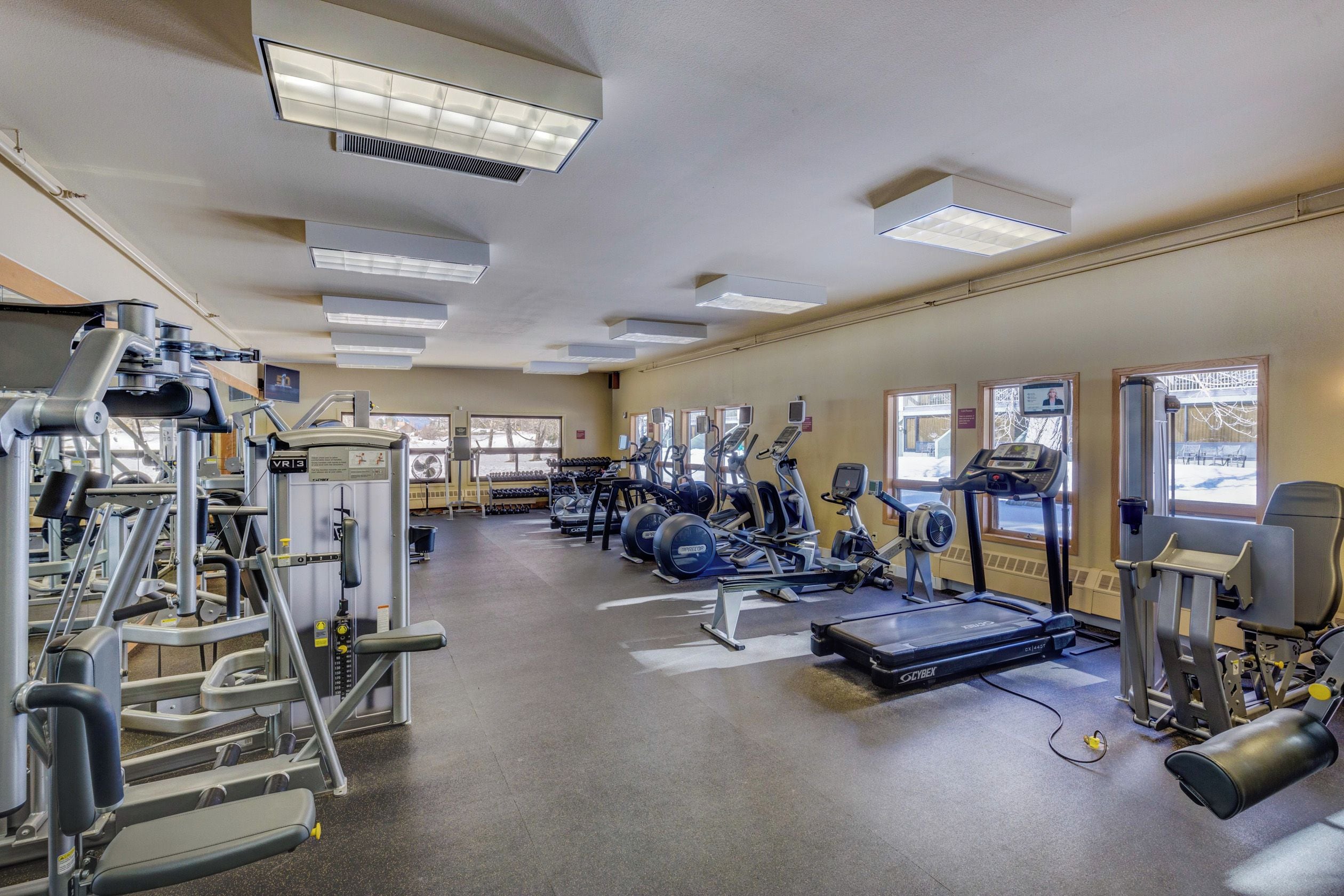 A gym with various exercise equipment, including treadmills, elliptical machines, and weight machines.