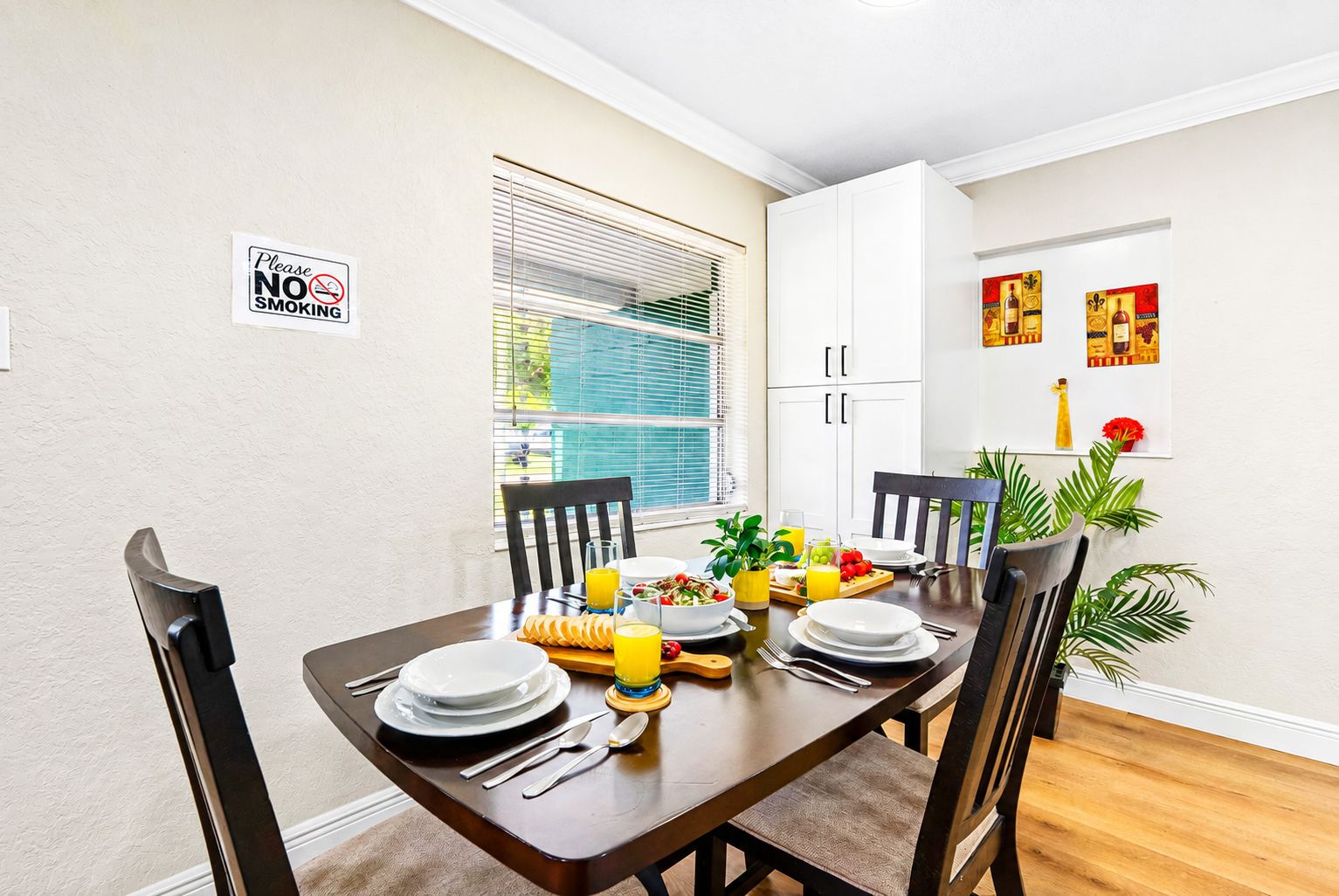A dining area with a table set for four, including plates, cutlery, and a fruit bowl.
