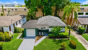 A residential property with a two-car garage, a well-maintained lawn, and a variety of mature trees.