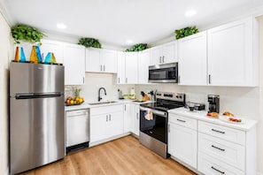 Una cocina moderna con gabinetes blancos, electrodomésticos de acero inoxidable y piso de madera.