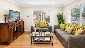 A living room with a glass coffee table, two sofas, a wooden cabinet, and a painting on the wall.