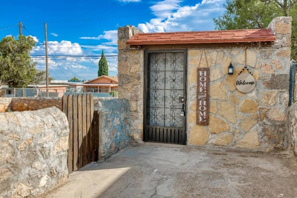 Una casa de piedra con una reja de metal, una puerta de madera y un letrero que dice 'HOME sweet HOME'.