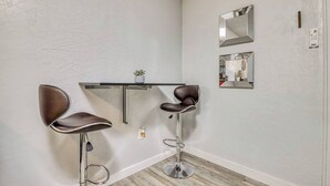 A corner room with two brown leather chairs, a small table, a mirror, and a wall-mounted phone.