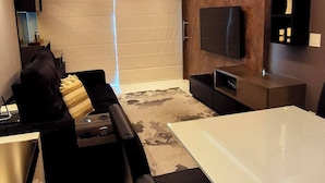 Ein modernes Wohnzimmer mit einer Couch, einem Esstisch und einem an der Wand befestigten Fernseher.