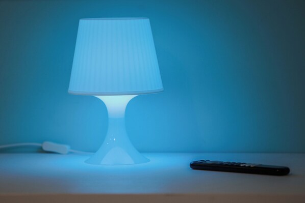 Une table avec une lampe blanche et une télécommande.