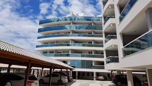 A multi-story building with balconies and a covered parking area. - 1 bedroom apartment (1 bedroom) Le Bon Vivant (Praia Grande Arraial do Cabo)