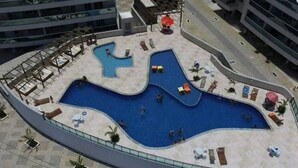 A rooftop pool with a unique wavy design, surrounded by lounge chairs and umbrellas. - 1 bedroom apartment (1 bedroom) Le Bon Vivant (Praia Grande Arraial do Cabo)