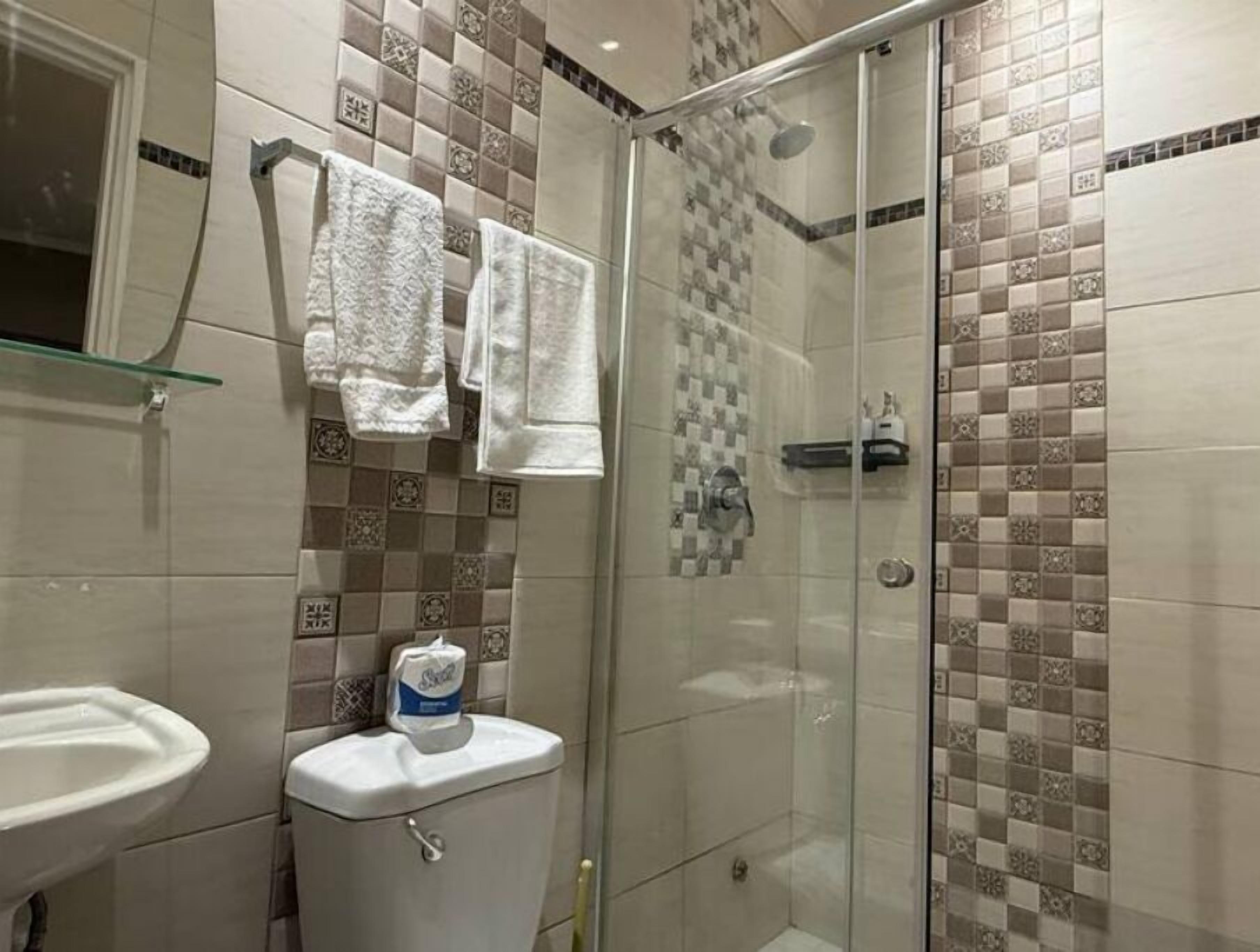 Un baño con ducha de vidrio, inodoro y lavamanos.
