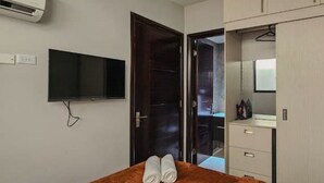 A bedroom with a bed, a TV mounted on the wall, a wardrobe, and a bathroom visible through an open door. - 2-Bedroom Apt in Cinta Costera (Panamá)
