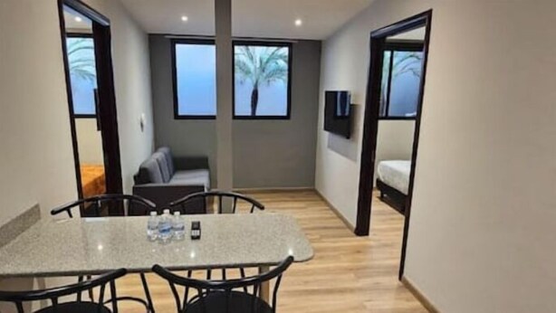 A compact room with a dining table, chairs, a sofa, and a bed. - 2-Bedroom Apt in Cinta Costera (Panamá)