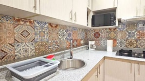A kitchen with a sink, stove, and microwave. - 2-Bedroom Apt in Cinta Costera (Panamá)