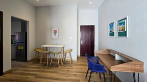 A modern kitchen with a refrigerator, a dining area with a table and chairs, and a wooden bench.