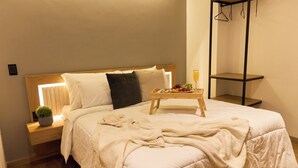 A neatly made bed with a bedside table, a small plant, and a tray with fruit and a glass of orange juice. - Rosa Negra Suite w/ Jacuzzi Near Stadium (Medellín)