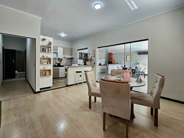 A modern kitchen with a central island, dining area with chairs, and a view into the dining room.