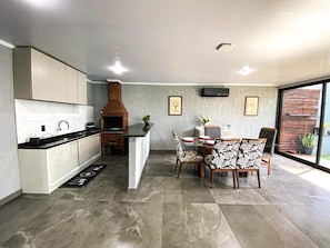 A modern kitchen with a built-in oven, dining area with patterned chairs, and a large window.