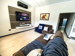 Un salon avec un canapé, un téléviseur fixé au mur et un tableau accroché au mur.