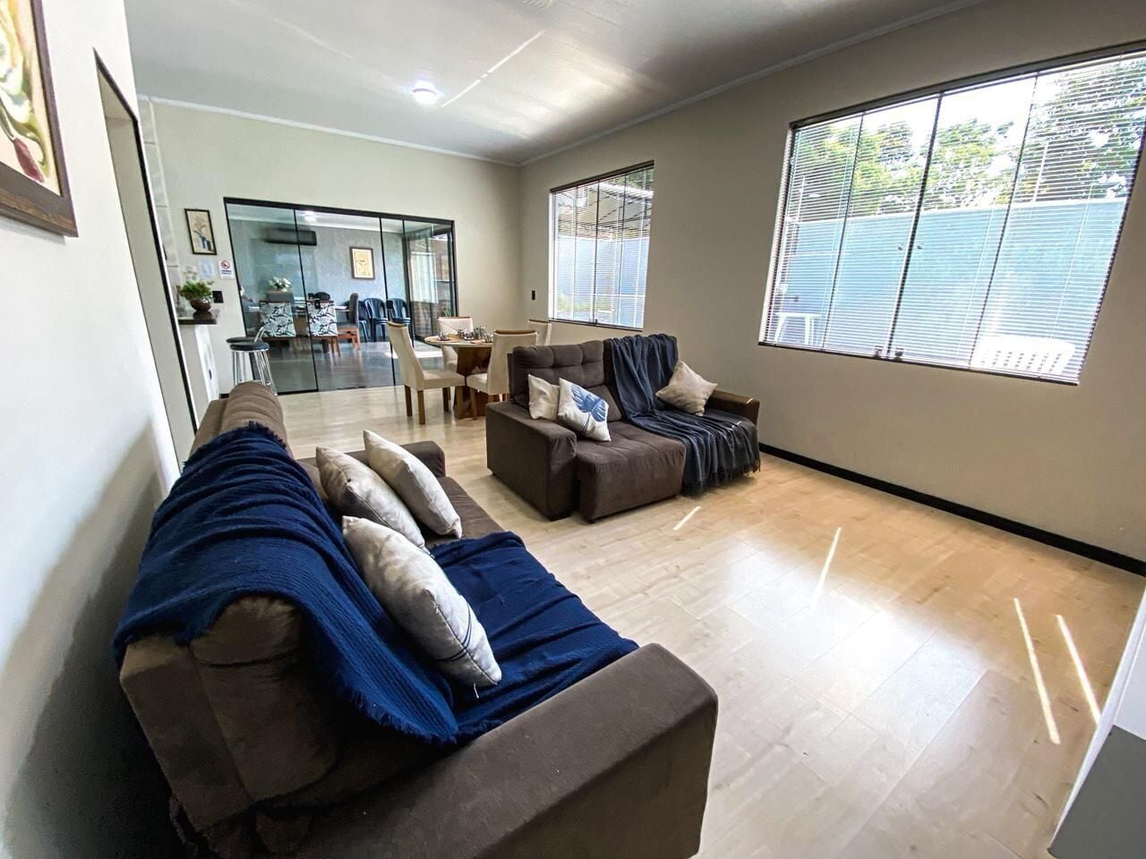 Sala de estar com dois sofás, uma mesa de centro e um espaço de jantar com cadeiras.
