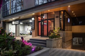 A modern building with a gym on the ground floor, a restaurant on the second floor, and a well-lit entrance with steps leading up to the door. - Stadio Aparta-suite Bliss Rosa Negra (Medellín)