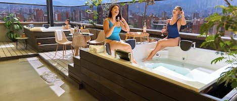 A rooftop terrace with a hot tub, seating area, and a city view.