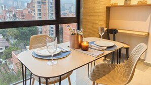 A dining area with a table set for two, a candle, and a bottle of champagne. - Cozy Comforts at Rosa Negra Stadio (Medellín)