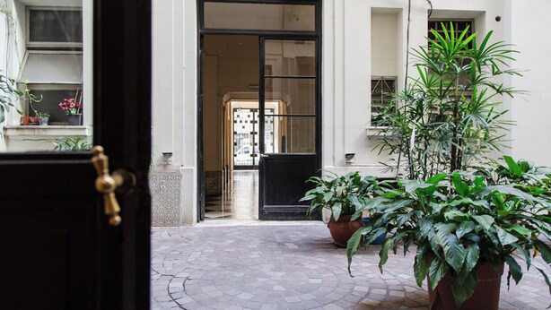 A courtyard with a tiled floor, a black door, and potted plants. - Alvear Bioy Residence by Argenhost (Buenos Aires)