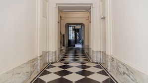 A hallway with a black and white checkered floor, white walls, and a door at the end. - Alvear Bioy Residence by Argenhost (Buenos Aires)