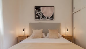 A neatly made bed with two bedside tables, each with a lamp, and a framed abstract artwork above the bed. - Alvear Bioy Residence by Argenhost (Buenos Aires)