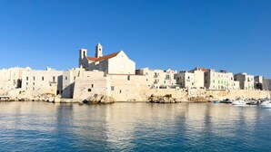 Un pueblo costero con edificios históricos, una iglesia destacada y un puerto con barcos.