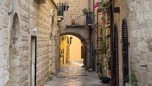 Un estrecho callejón de piedra con arcos y balcones, que conduce a un edificio con una puerta de madera.