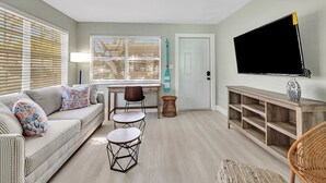 Una sala de estar con un sofá, dos sillones, una mesa de centro, un televisor y un mueble de televisión de madera.