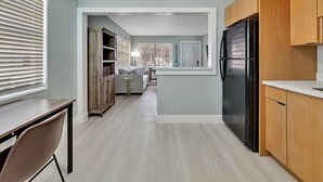Una cocina moderna con armarios de madera, un refrigerador negro y un comedor con una mesa y sillas.