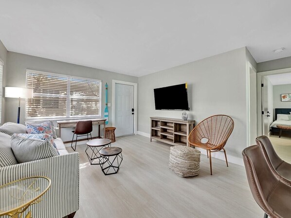 A modern living room with a sofa, chairs, a coffee table, a TV, and a bookshelf. - Beachside 1BR Apt Walk to Hollywood & Dania Beach (Hollywood)