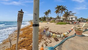 Una playa con un faro, palmeras y una orilla de arena.