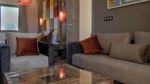 Una sala moderna con dos sofás, una mesita de centro de vidrio y una lámpara de pared.